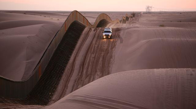 a truck drives along the border wall at the US/Mexico border